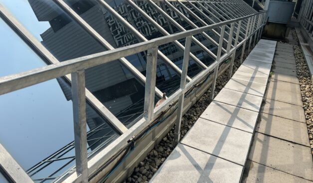 Industrial safety inspector examining rooftop guardrails installed for fall protection compliance in Ontario.