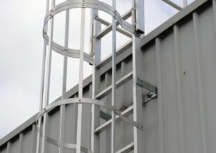 Fixed access ladder with safety cage on industrial building requiring inspection and compliance in Ontario