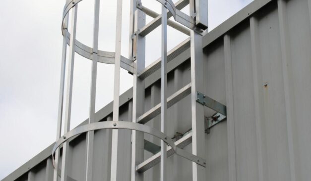 Fixed access ladder with safety cage on industrial building requiring inspection and compliance in Ontario