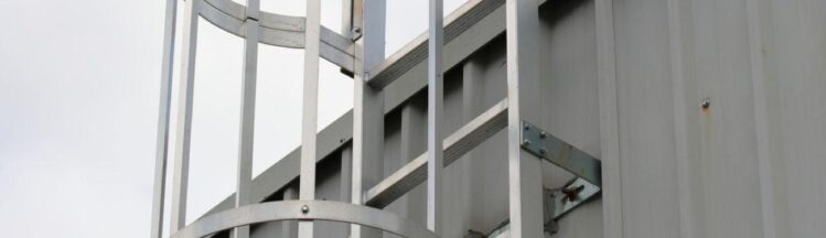 Fixed access ladder with safety cage on industrial building requiring inspection and compliance in Ontario