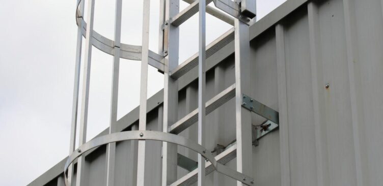 Fixed access ladder with safety cage on industrial building requiring inspection and compliance in Ontario