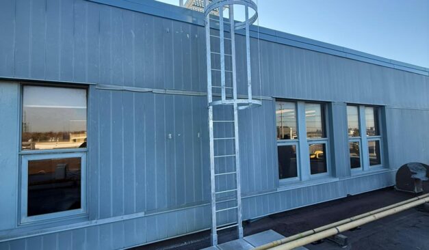Fixed access ladder with engineered dimensions and safety cage installed on industrial building in Ontario