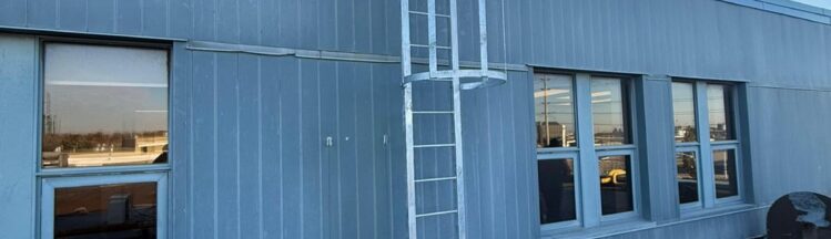 Fixed access ladder with engineered dimensions and safety cage installed on industrial building in Ontario