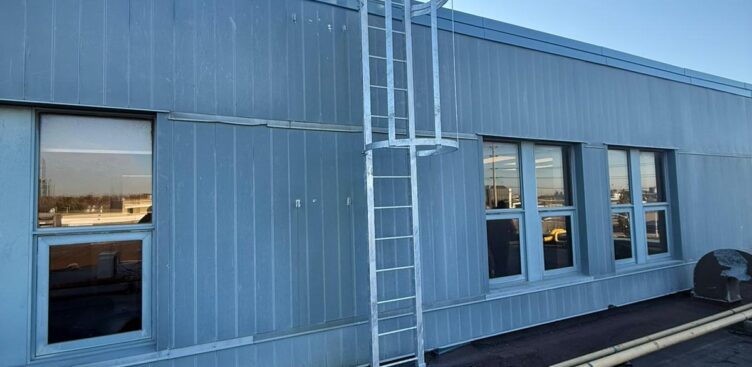 Fixed access ladder with engineered dimensions and safety cage installed on industrial building in Ontario