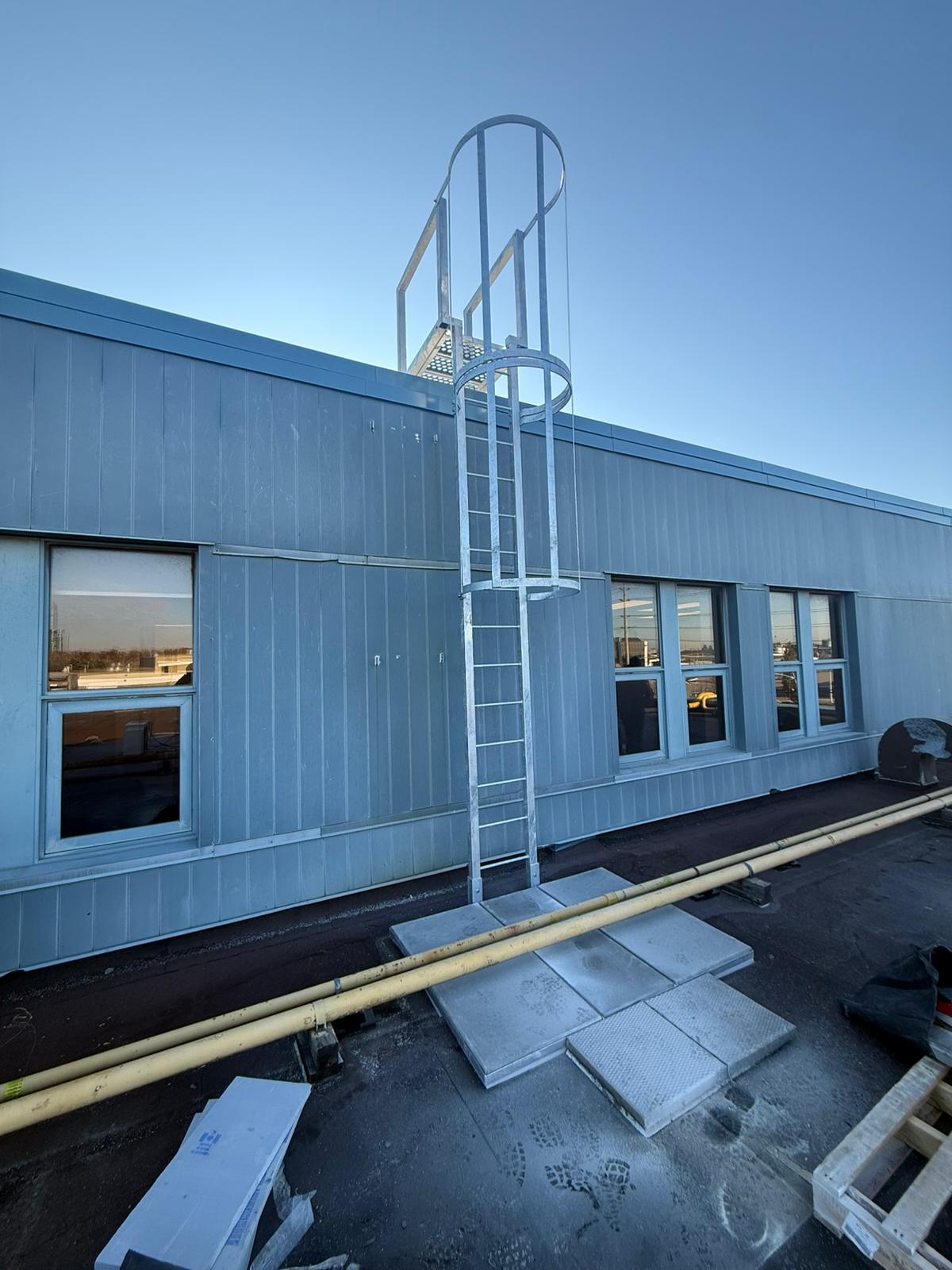 Fixed access ladder with engineered dimensions and safety cage installed on industrial building in Ontario